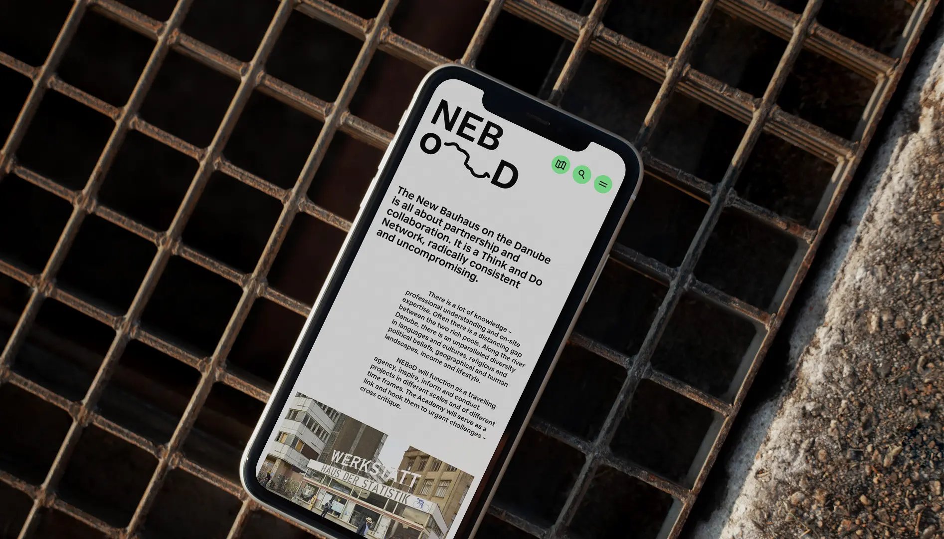 Smartphone showing the NEBoD website, lying on a rusty metal grate