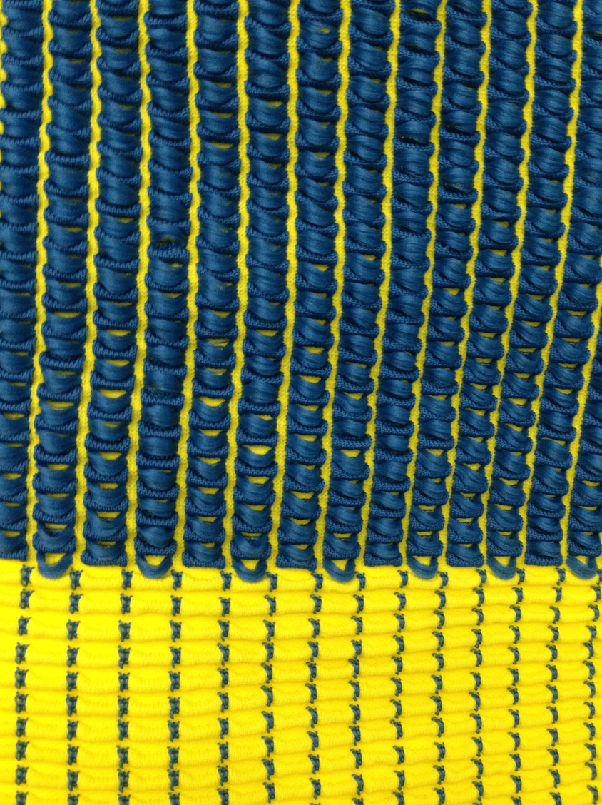Close-up of a knitted textile with blue loops over a yellow base